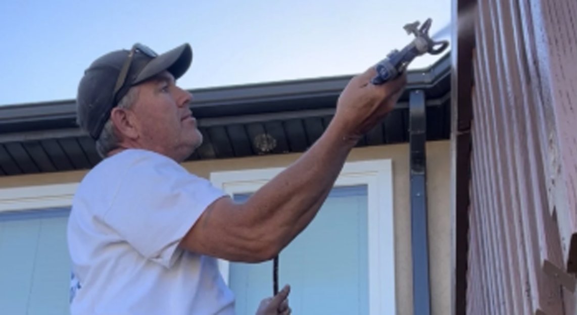 Howard spray-painting the exterior trim of a home in St. George, Utah
